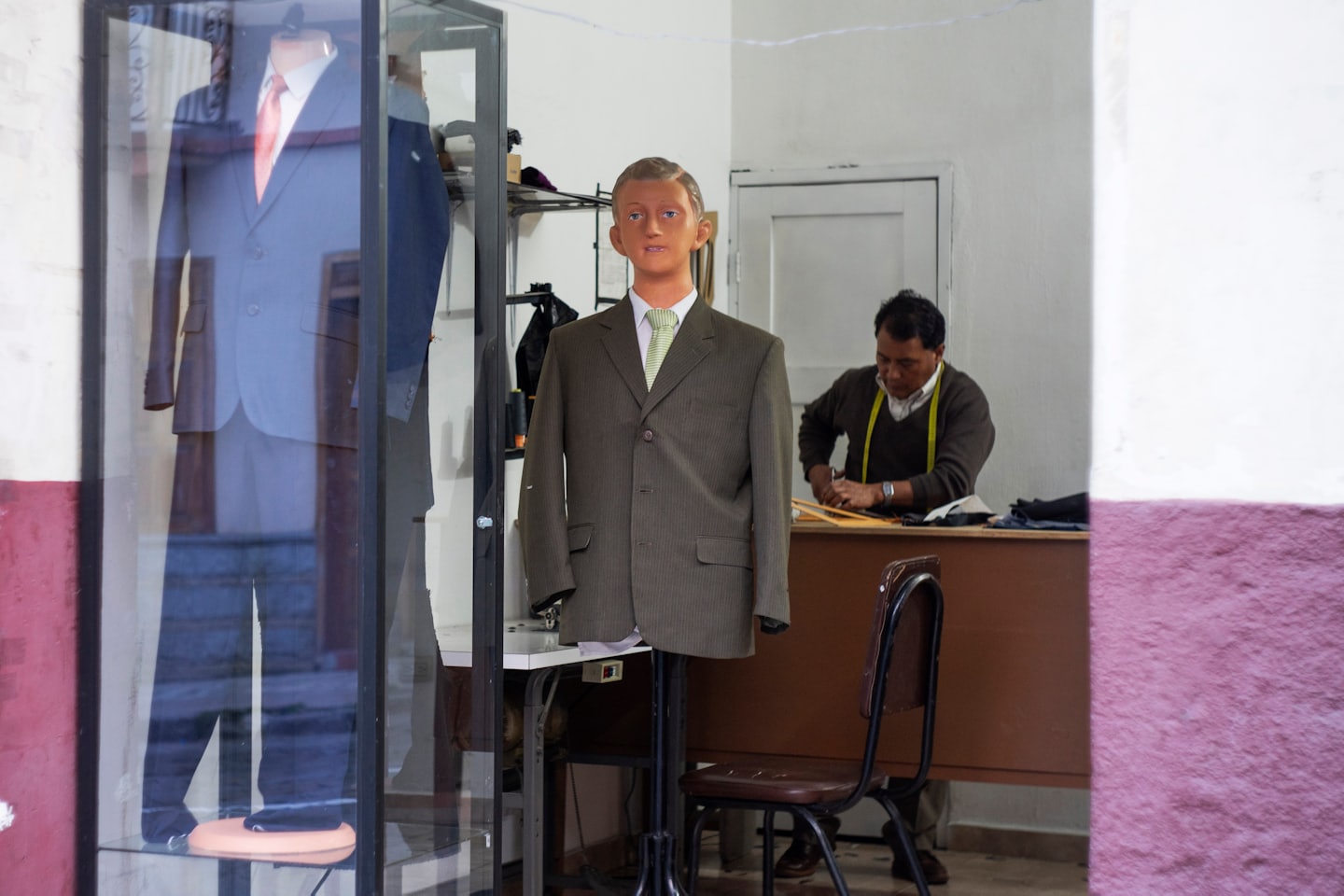 Tailor cutting fabric with measuring tape around neck.