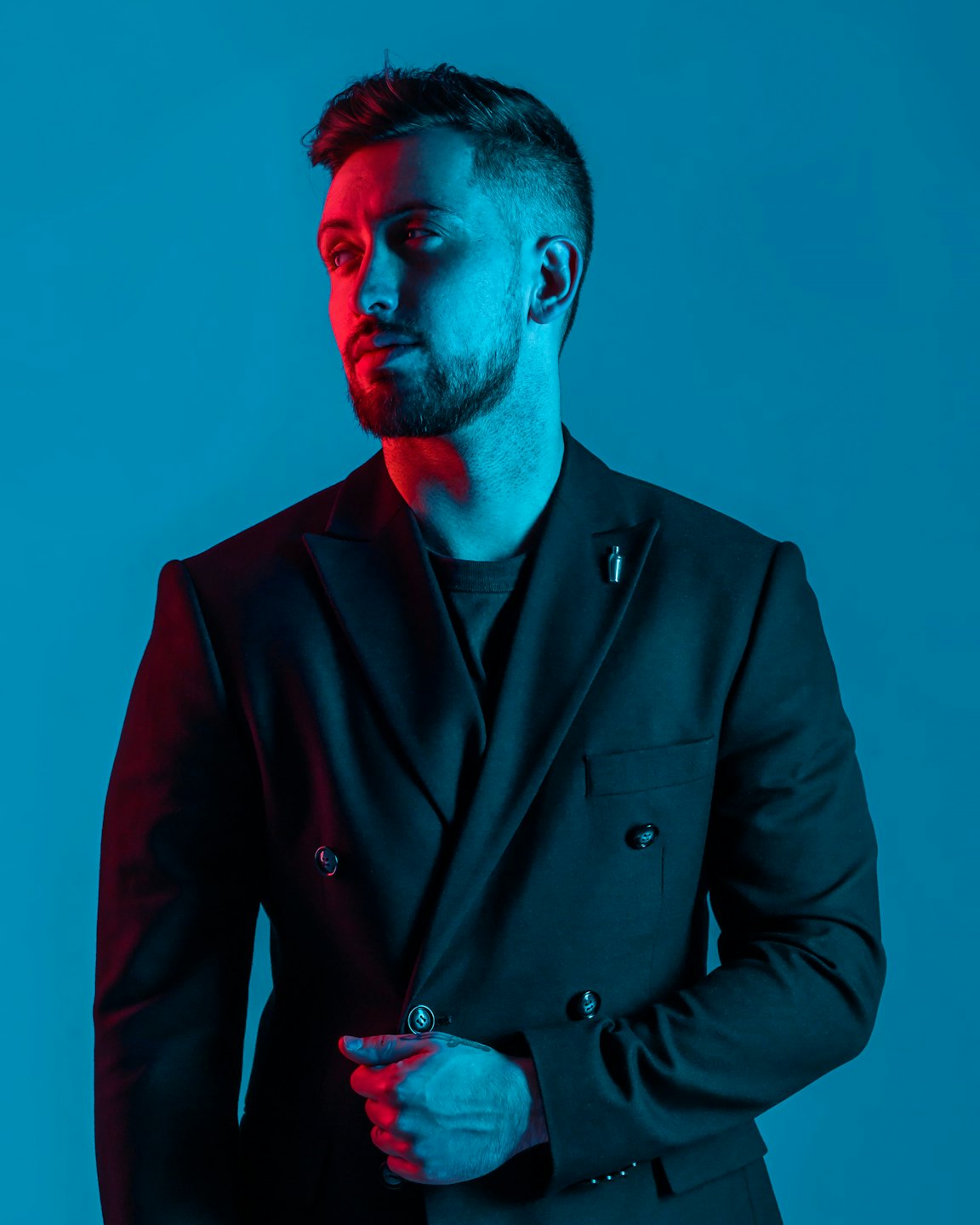 Man in a dark suit adjusts his lapel.