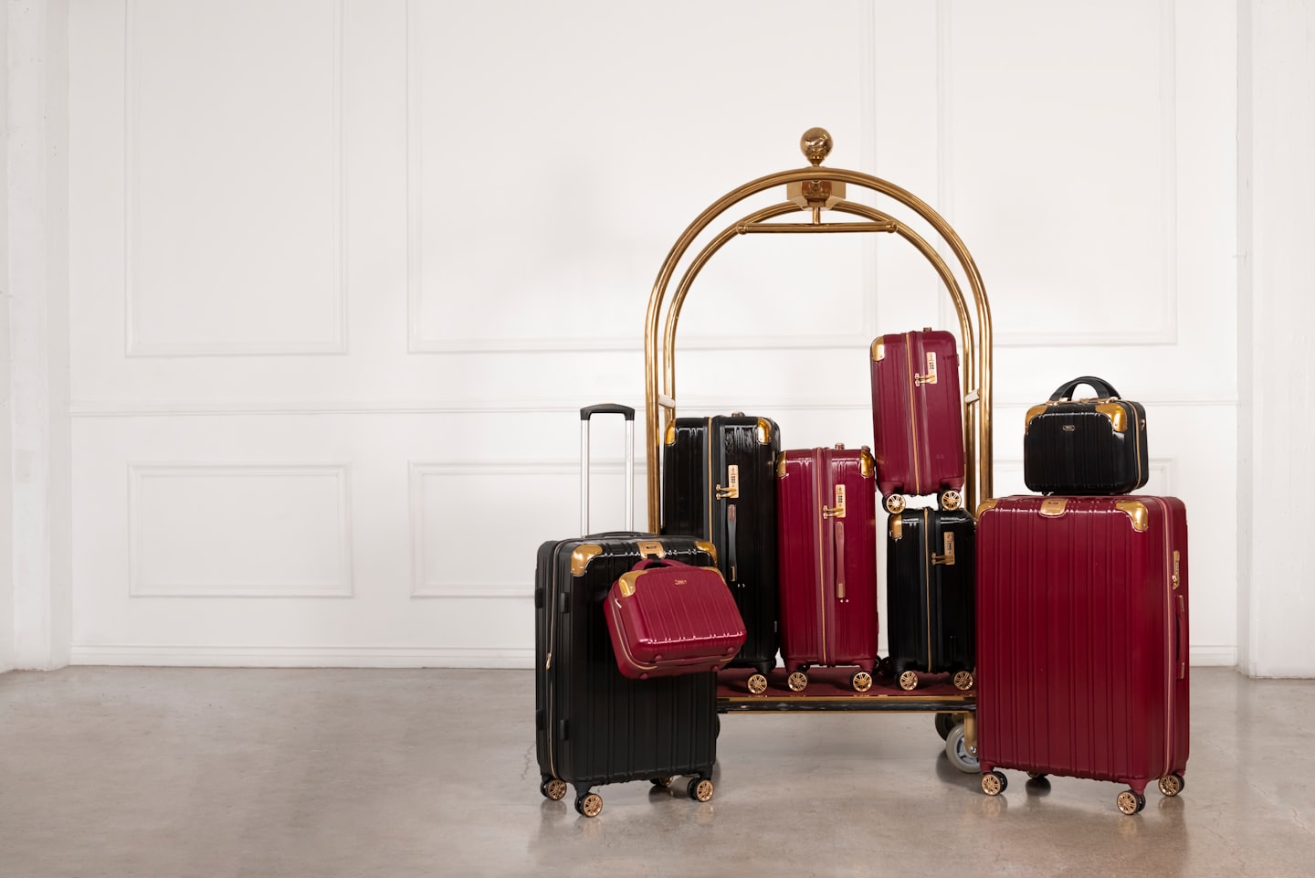 Black and burgundy suitcases on a golden hotel bell cart.