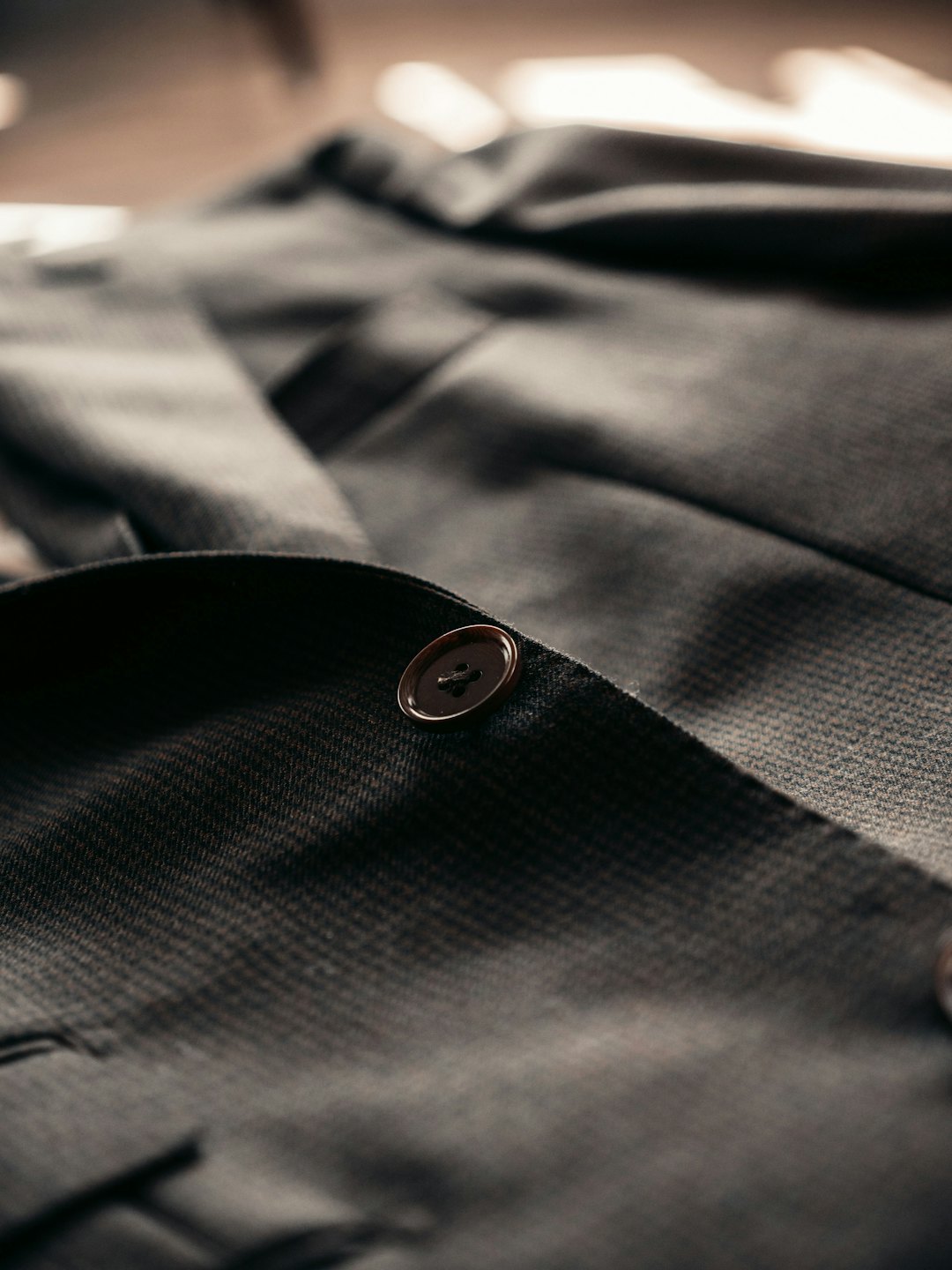 A single brown button attached to a textured suit jacket.