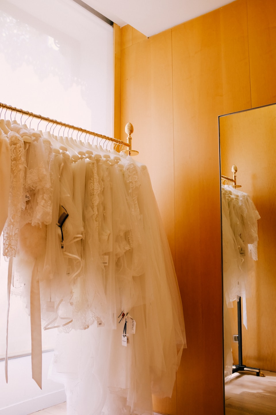 Elegant wedding dresses hang on a gold rail in a boutique.